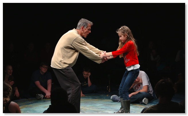 Image of performer working with young students on a stage